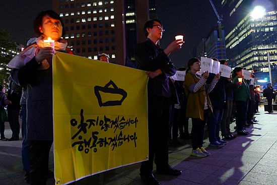 9일 오후 세월호 침몰 사고 진상규명을 요구하는 촛불행진에 참여한 시민들이 서울 종로 보신각 앞에서 촛불과 함께 '잊지않겠습니다 행동하겠습니다'라고 쓰인 펼침막을 들고 있다. 
