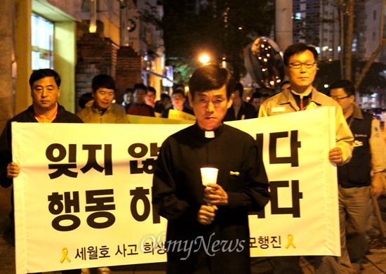  14일 저녁 경남 창원 천주교 진해중앙성당에서 '세월호 참사 희생자 진해지역 합동추모미사'가 열렸다. 미사 참가자들은 "잊지 않겠습니다. 행동하겠습니다"라고 쓴 펼침막과 촛불을 들고 거리행진을 했다. 이재영 신부가 맨 앞에 섰다.