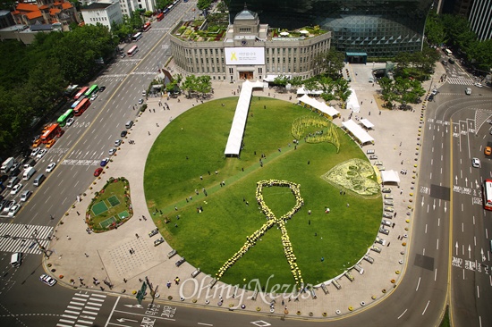 세월호 참사 한달째인 지난해 5월 16일 서울시청 앞 서울광장에서 시민들이 희생자를 추모하기 위한 인간리본 만들기 플래시몹에 참여하고 있다.