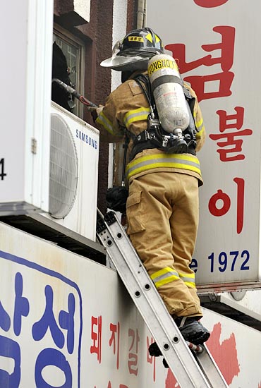  17일 오후 서울 중구 북창동에 위치해 있는 한 식당에서 화재가 발생해 긴급출동한 소방관들이 사다리를 타고 올라가 2층 유리창을 깨뜨리고 있다.