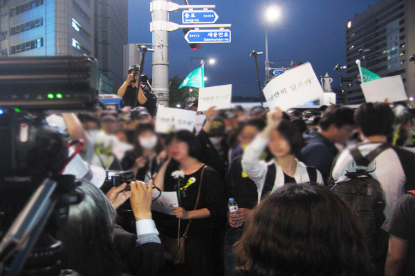 경찰들에게 둘러싸인 채 울음을 터트리는 침묵시위 참여자들