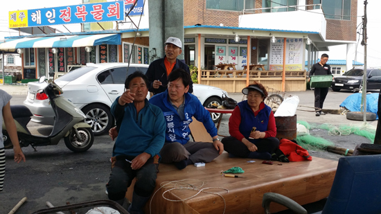 새정치 홍기업 강릉시장 후보가 지역 주민들과 담소를 나누고 있는 모습