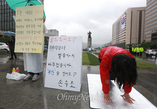 2014년 6.4지방선거를 하루 앞둔 3일 오후 손수조 새누리당 당협위원장이 서울 광화문광장에서 '도와주세요! 머리부터 발끝까지 바꾸겠습니다. '부산'을 믿어요! 손수조'가 적힌 피켓을 놓고 절을 하고 있다. 옆에서는 '중·고생 엄마'라고 밝힌 시민이 '오늘 세월호 49재. 세월호 아이들이, 유가족들이 살려달라 울부짖을 때 당신들은 도와주었나요? 도와주세요?? 표 구걸?? 16명의 실종자 찾아주세요'가 적힌 피켓을 들고 1인 시위를 하고 있다.