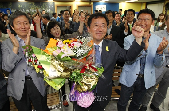 김석준 부산시교육감 후보가 4일 오후 부산 동구 자신의 선거사무실에서 TV 모니터를 통해 당선 확정이 보도되자, 지지자로부터 축하꽃다발을 건네받은 뒤 기뻐하고 있다.