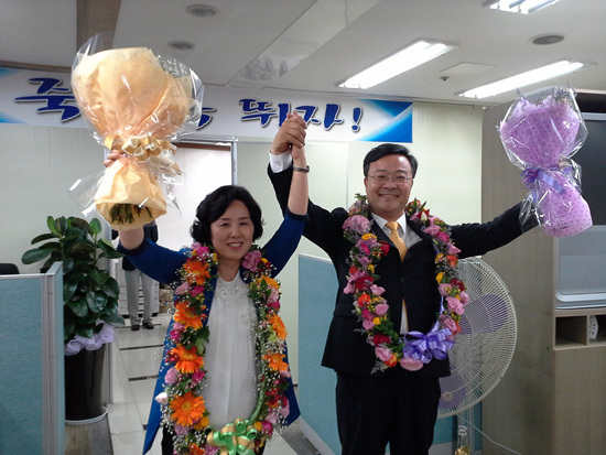 김성제 당선자가 부인과 함께 꽃다발을 들로 환호하고 있다. 
