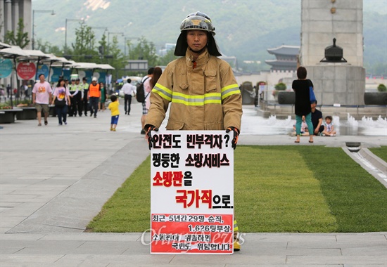 2014년 6월 9일 오후 서울 광화문광장에서 화재진압복을 입은 소방관이 지방직인 소방관의 '국가직 전환' '현장대응 소방인력 증원' '낡고 부족한 장비 현대화' 등을 요구하며 릴레이 1인 시위를 벌이고 있다.