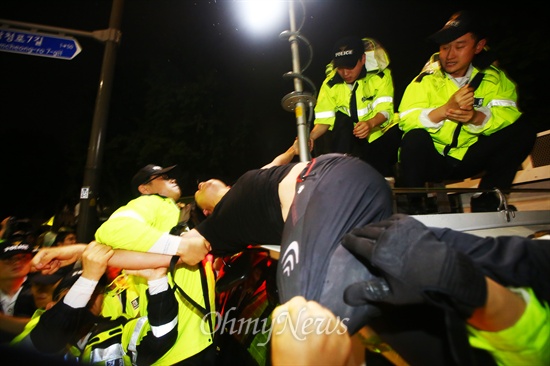 경찰이 차 위에 올라간 집회 참가자를 강제로 끌어내리고 있다.