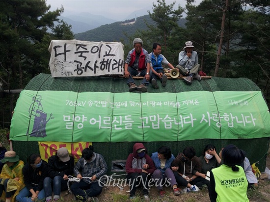  밀양 단장면 용회마을  산 정상 부근에 있는 101번 송전철탑 부지의 움막농성장에 주민들이 올라가거나 에워싸고 앉아 강제철거 행정대집행에 대비하고 있다.