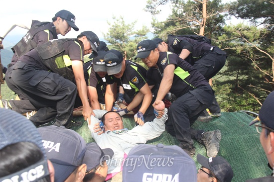 11일 오후 밀양 단장면 용회마을 승학산 정상에 있는 101번 송전철탑 현장의 움막농성장 철거 행정대집행 과정에서 충돌이 발생한 가운데, 경찰이 움막 지붕에 올라가 있던 주민들을 강제로 끌어내리고 있다.