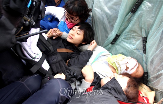 경찰이 들이닥치자 통합진보당 김재연 국회의원이 연대단체 회원들과 함께 움막 앞에 스크럼을 짜고 지키고 있다. 당시 김재연 의원은 팔목에 상처를 입기도 했다.