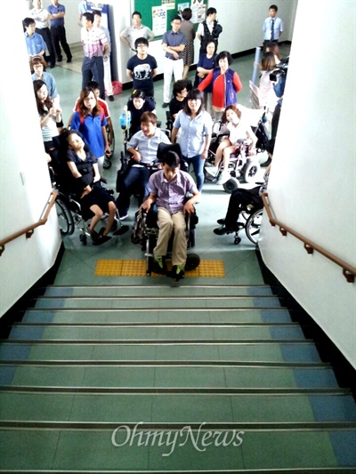 장애인단체들이 17일 오전 창원시청 건물 1~2층 사이 중간층에 있는 브리핑룸에서 기자회견을 하려고 했지만 계단이 되어 있어 올라가지 못하자 항의하는 일이 벌어졌다. 사진은 휠체어를 탄 장애인들이 1층에 도착했지만 계단을 올라가지 못하고 있는 모습.