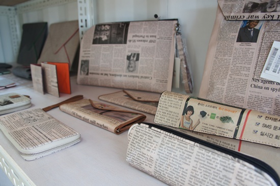 진열대 위에 버려진 신문을 활용해 만든 지갑과 가방 등이 놓여 있다. 