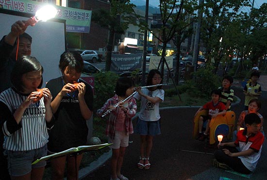 모락산 아이들이 주관한 의왕시 촛불추모회에서 모락산 아이들이 연주를 하고 있고, 김치하 촌장이 불을 밝혀주고 있다.