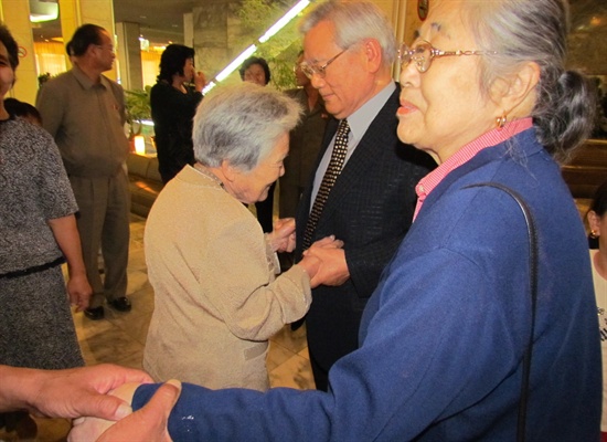목사님과 북한에 사는 목사님 누나가 두 손을 맞잡고 있다.