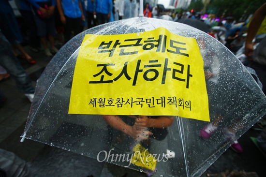 21일 오후 서울 중구 청계광장에서 세월호 침몰사고 진상규명을 위한 시민대회에서 한 시민의 우산 위에 '박근혜도 조사하라' 손피켓이 붙어 있다.
