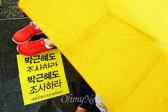 지난 21일 오후 서울 중구 청계광장에서 세월호 침몰사고 진상규명을 위한 시민대회에서 우산을 쓴 참가자 앞에 '박근혜도 조사하라' 손피켓이 놓여 있다.