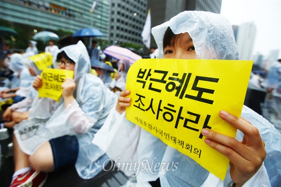 21일 오후 서울 중구 청계광장에서 세월호 침몰사고 진상규명을 위한 시민대회에서 한 시민이 우의를 입고 손피켓을 들고 있다.