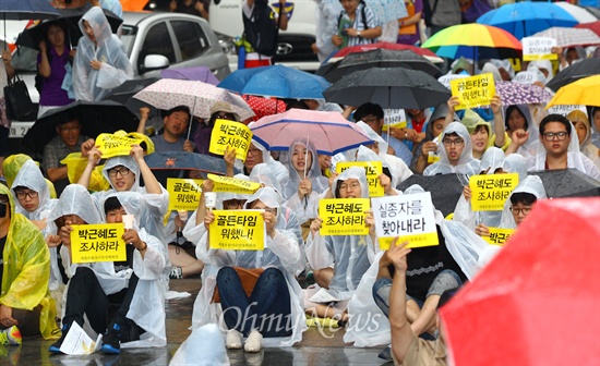 21일 오후 서울 중구 청계광장에서 세월호 침몰사고 진상규명을 위한 시민대회가 열린 가운데 참가한 시민들이 우의를 입고 손피켓을 들고 있다.