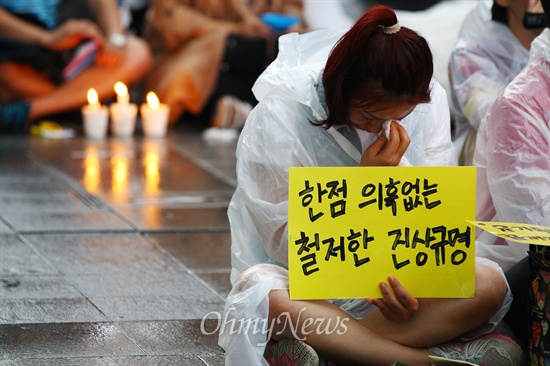 21일 오후 서울 중구 청계광장에서 세월호 침몰사고 진상규명을 위한 시민대회에서 시민들이 우의를 입고 손피켓을 들고 있다.
