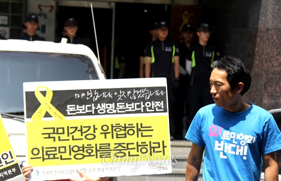 전국보건의료산업노동조합 한 조합원이 '의료 민영화'에 반대하는 피켓을 들고 새누리당 경남도당 앞에 서 있다.