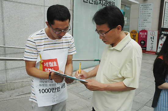 강남역을 지나가는 한 시민이 김제동의 요청에 세월호 진상규명과 재발방지를 위한 서명에 동참하고 있다. 