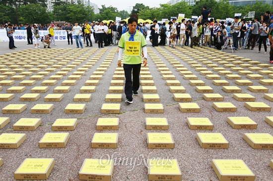 15일 오전 서울 여의도광장에 놓인 4.16참사특별법 제정천만서명서가 담긴 상자들 사이로 세월호 희생자 유가족이 걸어 나오고 있다.