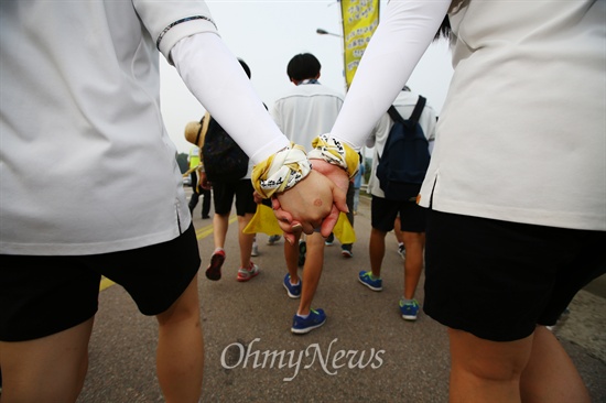 지난 2014년 7월 15일 세월호 생존 학생들이 경기도 안산에서 국회를 향한 도보 행진을 하고 있다. 두 생존자 친구가 손을 꼭 잡고 걷고 있다.