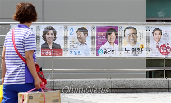 7.30 재보선 공식 선거운동이 시작된 17일 오전 서울 동작구 중앙대 정문 앞에 부착된 동작을 후보자 선거벽보를 한 시민이 쳐다보고 있다.