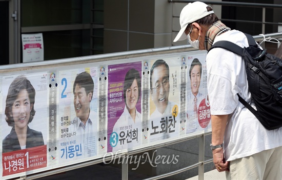 7.30 재보선 공식 선거운동이 시작된 17일 오전 서울 동작구 중앙대 정문 앞에 부착된 동작을 후보자 선거벽보를 한 시민이 쳐다보고 있다.