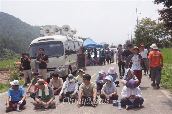 송전탑 건설을 반대하는 시민들이 길바닥에 앉아 한전과 정부를 비판하고 있다.