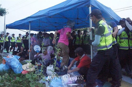 경찰들이 할머니들이 앉아있는 천막을 에워싸기 위해 달려들고 있다. 
