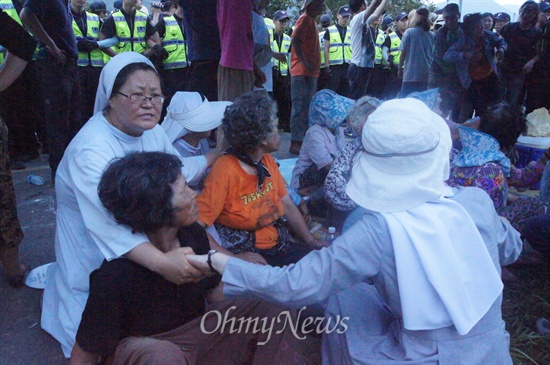 수녀님들이 할머니들을 경찰로부터 보호하기 위해 손으로 에워싸고 있다.