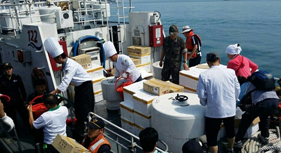 지난 20일, 자원봉사자들이 만든 특식을 배로 옮겨 싣고 있다. 