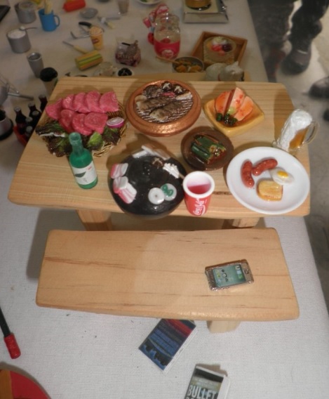음식이 놓여져 있는 탁자는 손바닥만한 크기다. 탁자에 놓여 있는 음식과 아래에 있는 핸드폰 모두 미니어처다.