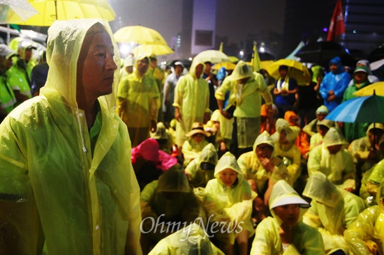 25일 오전 서울광장에서 유가족과 수만명의 시민들이 '세월호 참사 100일 추모 문화제'를 마치고 행진을 시도하자 경찰이 막아서 유가족들이 비가 쏟아지는 바닥에 앉아 있다.