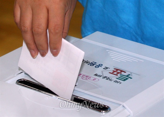 전국 15개 지역에서 7·30 재보궐 선거가 실시된 30일 오전 서울 동작구 상도1동 제5투표소에서 유권자가 기표를 마친 뒤 투표용지를 투표함에 넣고 있다.