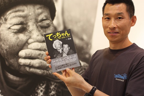일본인 한센인 권철 작가가 박성태 작가의 작품인 민선식 할머니 사진 앞에서 그가 쓴 일본 한센인 텟짱의 책을 들어 보이고 있다.