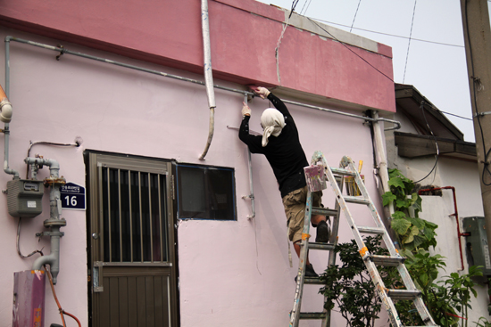 건물 외벽에 페인트칠을 하고 있는 양수현 작가. 
