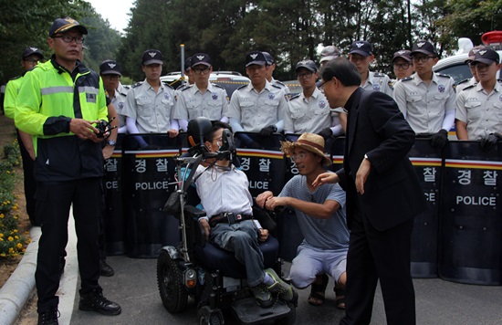 충북장애인차별철폐연대 일부 회원들이 휠체어를 타고 음성 꽃동네 행사장 입구로 가려다 경찰에 의해 저지당하고 있다. 