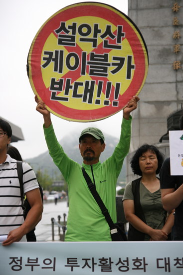 19일 서울 종로구 광화문 광장 이순신 장군 앞에서 설악녹색연합 박그림 대표가 '설악산 케이블 반대' 피켓을 들고 정부의 투자활성화 정책을 비판했다.