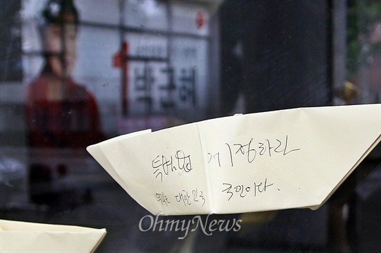 기자회견에 참석한 이들은 손수 접은 노란 종이배에 메시지를 담아 새누리당 광주시당사에 붙이기도 했다. 노란 종이배 너머에 박근혜 대통령의 얼굴이 담긴 현수막이 걸려 있다.
