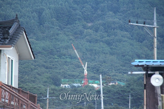 한국전력공사는 밀양 상동면 고정마을에 있는 과수원에 '신고리-북경남 765kV 송전선로' 115번 철탑 공사를 벌이고 있다. 사진은 마을 주택 사이로 보이는 철탑 공사장 모습.