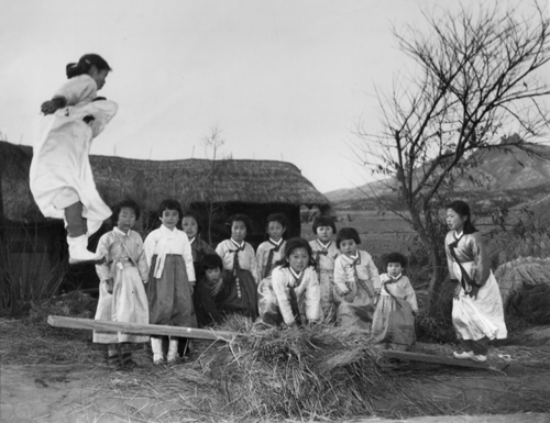 전란 중이지만 설빔을 차려입은 천진난만한 소녀들이 마을 공터에서 민속놀이인 널뛰기를 하고 있다(1953. 2.). 