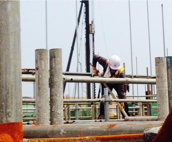 한 건설노동자가 지상 3m 높이에서 안전장치 없이 건설자재를 옮기고 있다.