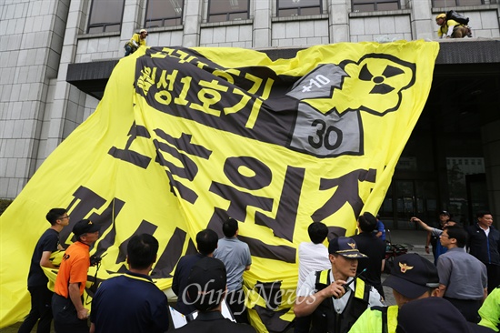 환경운동연합 회원들이 20층짜리 프레스센터 옥상에서부터 펼치고 내려온 대형현수막을 바닥에 내리고 있다.