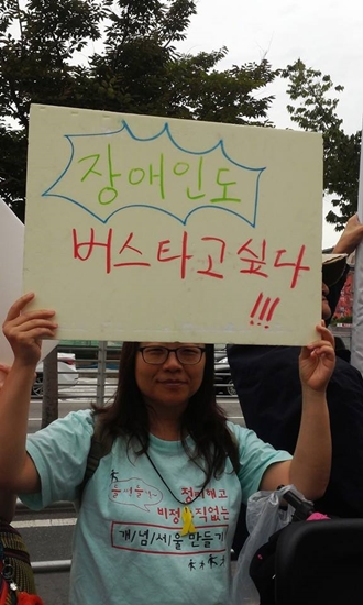 "장애인도 버스 타고 싶다" 는 손피켓을 전장연  활동가가 들고 있다.