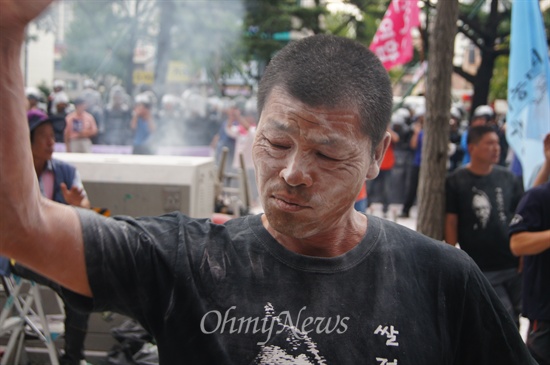 18일 오후 새누리당 경북도당 앞에서 열린 농민대회에서 한 농민이 경찰이 뿌린 소화기 가루를 뒤집어쓴 채 오른손을 들어 분노의 결의를 표하고 있다.