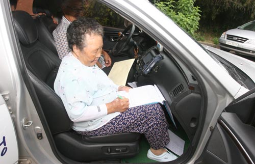 외딴 마을 할머니들이 택시에 탄 다음 운행장부에 서명을 하고 있다. 전라남도가 금명간 운행할 '100원 택시'의 모습이다.