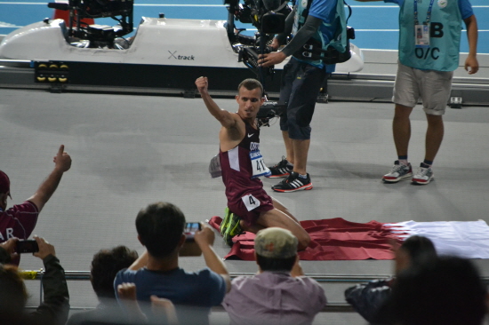  남자 5000미터 금메달을 딴 알 가르니(카타르)가 국기 위에 무릎 꿇고 앉아서 기뻐하고 있다.