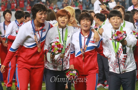 1일 오후 인천 문학월드컵경기장에서 열린 '2014 인천아시아경기대회' 여자축구 시상식에서 금메달을 획득한 북한 축구대표팀 선수들과 동메달을 획득한 한국 축구대표팀 선수들이 어깨동무를 하고 그라운드를 나서고 있다.